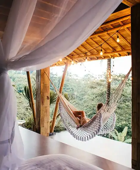 Unrecognizable traveler in hammock against bed in tropical resort