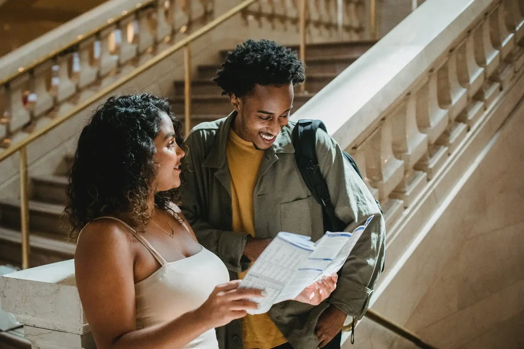 Happy multiracial couple smiling while exploring map in building free stock photo
